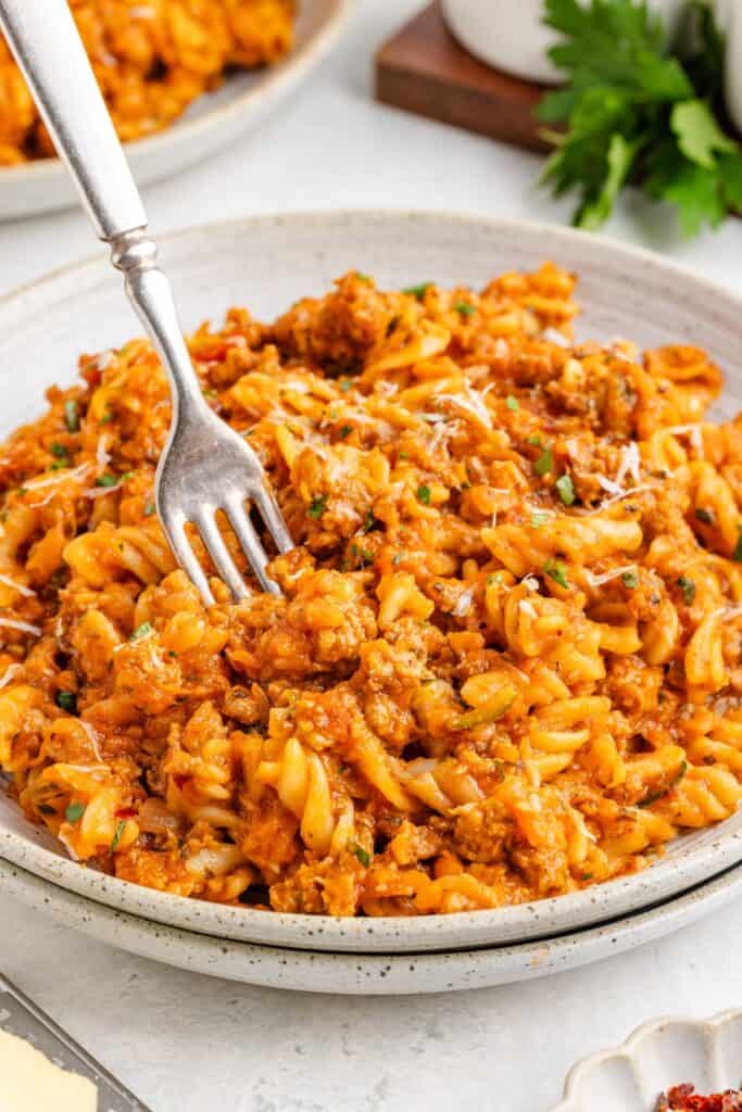 Ground turkey pasta with hidden veggies, grated cheese, and herbs; fork twirling noodles on the plate.