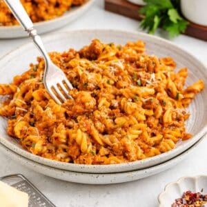 One pot ground turkey pasta with grated cheese, fork twirling noodles on plate.