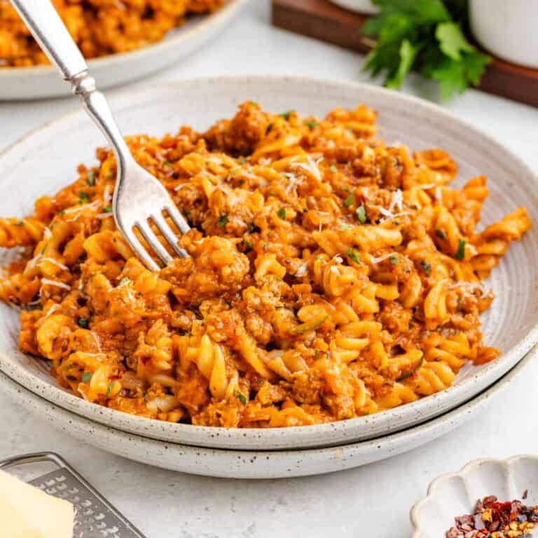 One pot ground turkey pasta with grated cheese, fork twirling noodles on plate.