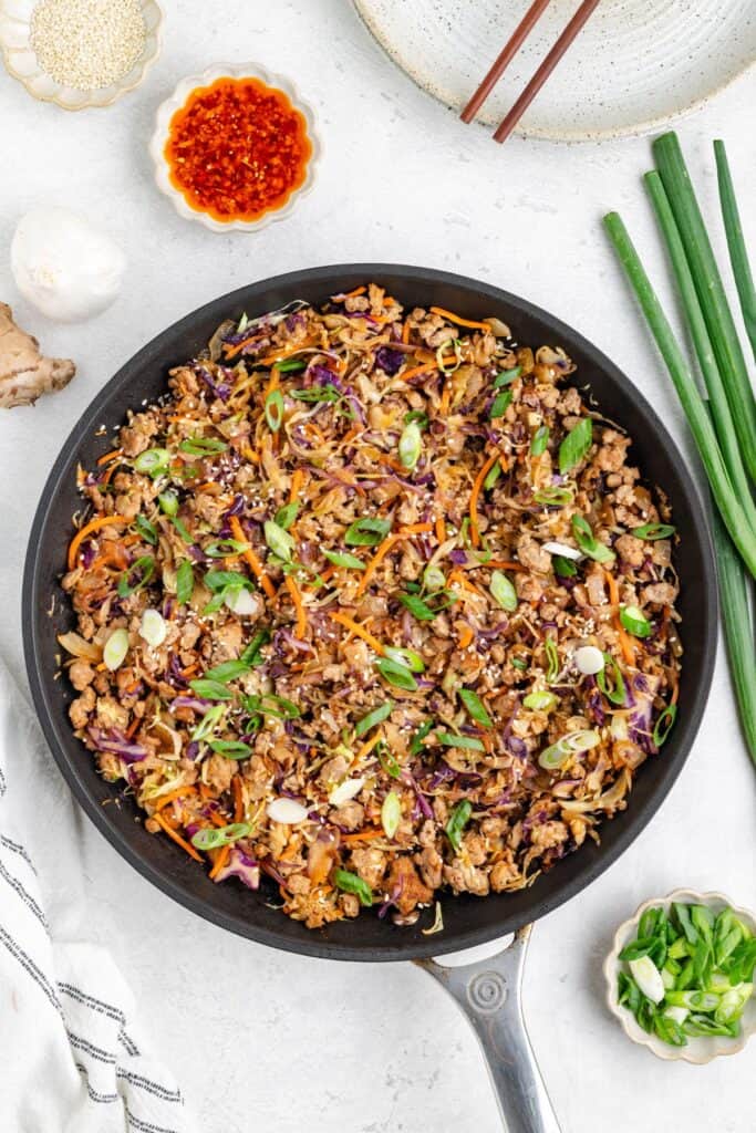 Skillet with Egg Roll in a Bowl with Ground Pork; condiments in small bowls.
