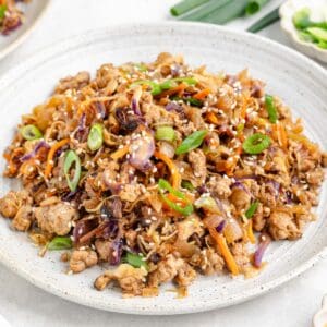 Egg Roll in a Bowl with Ground Pork, cabbage, carrots, onions, and sesame seeds on a white plate.