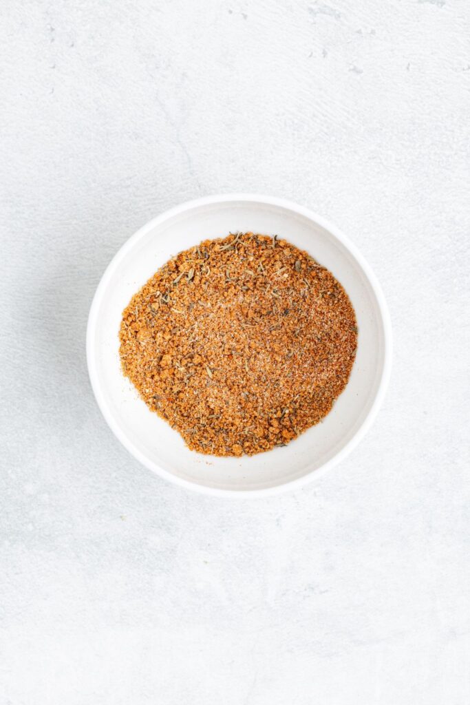 White bowl containing mixed ground spices sits on a light, textured surface.