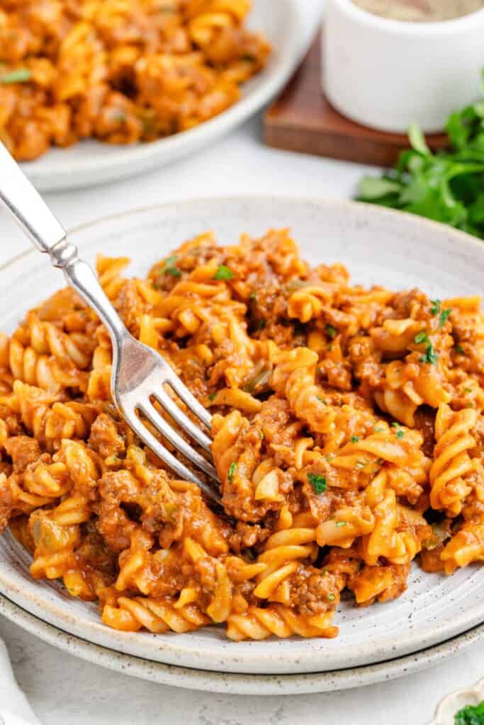 one pot Sloppy Joe Pasta with tomato meat sauce and herbs, served on a plate with a fork.