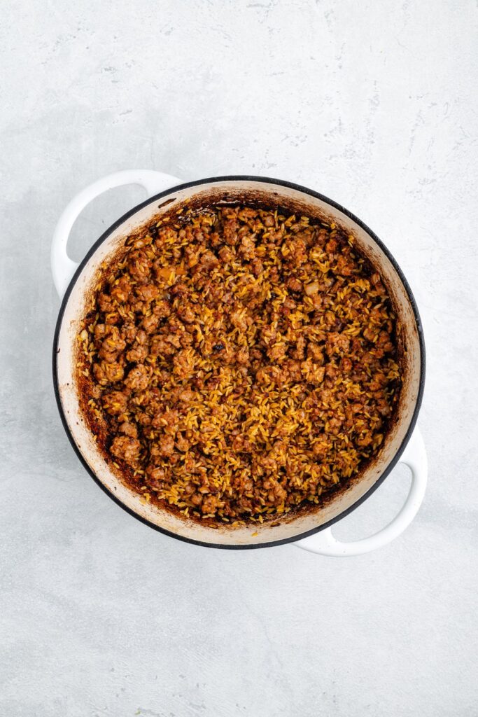 White pot containing cooked ground meat and rice mixture on a light gray surface.