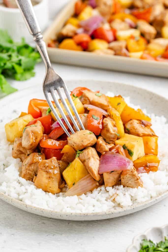White rice with Hawaiian Chicken Sheet Pan. A fork presses into the dish.