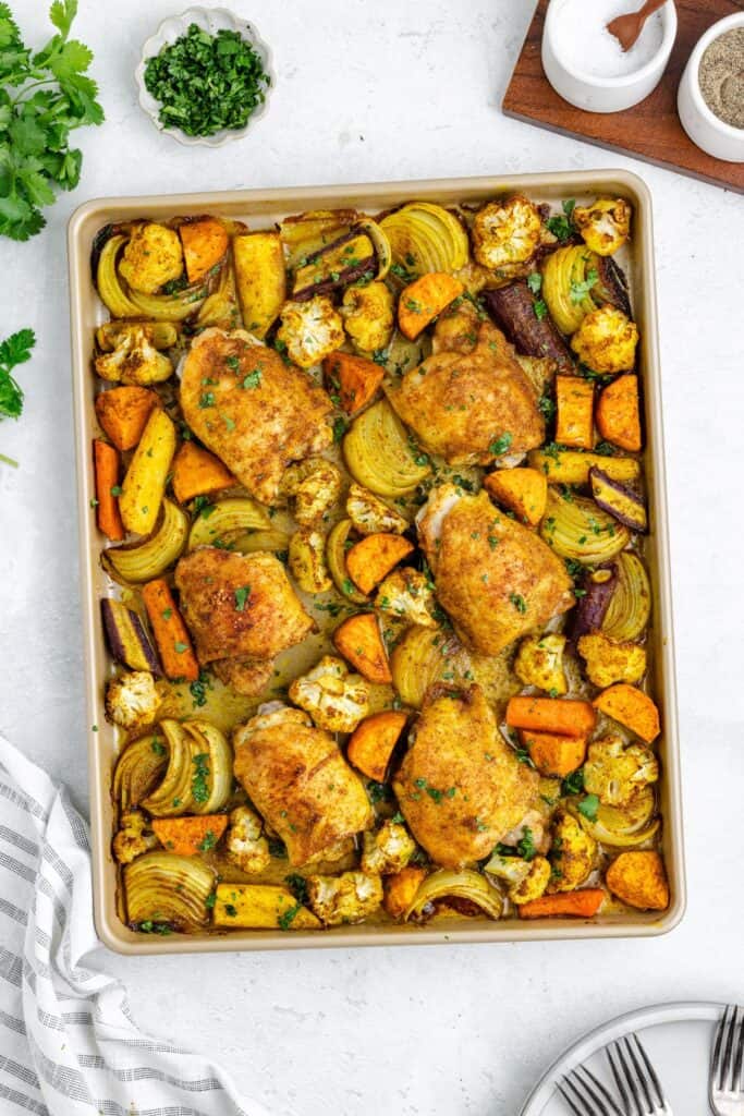 Roasted moroccan chicken with vegetables garnished with herbs.