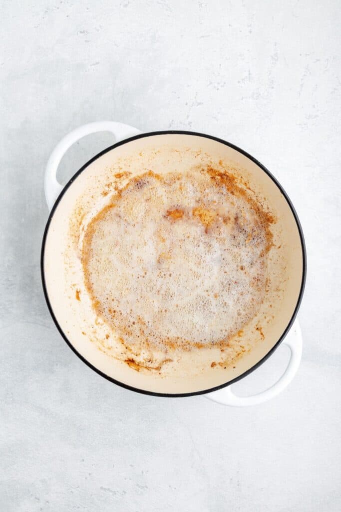 Foaming butter browning in a white enameled cast iron pot.