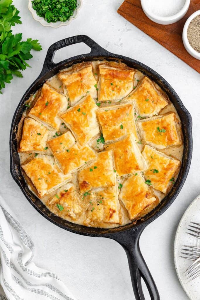 Leftover ham pot pie in a cast-iron skillet topped with golden-brown puff pastry squares.