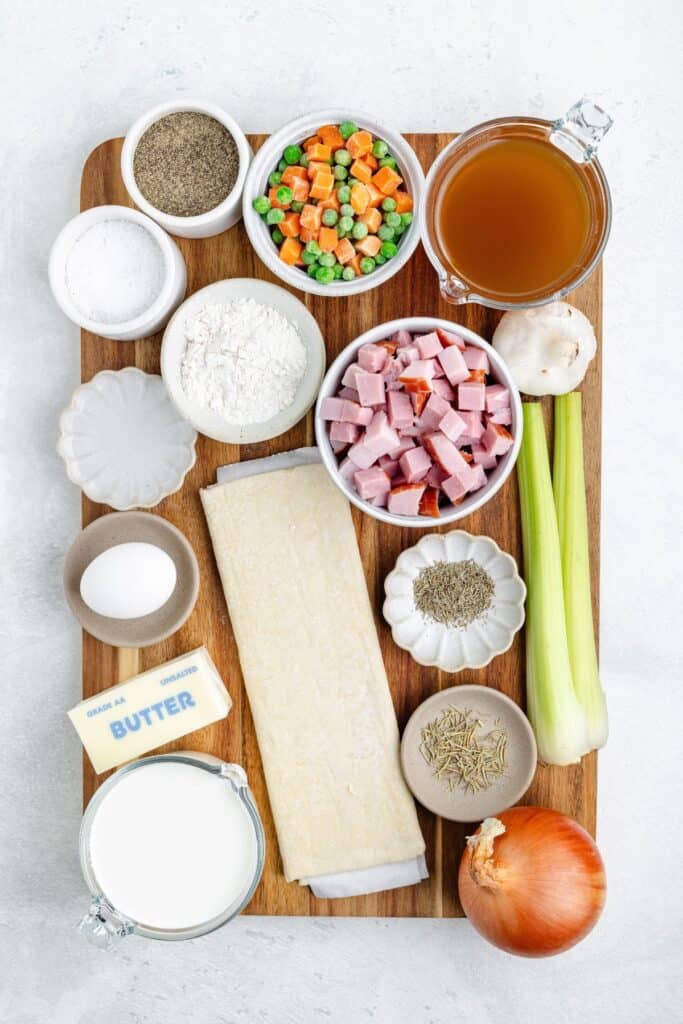 Ingredients for a savory pie, including diced ham, vegetables, pastry dough, broth, cream, butter, and seasonings.