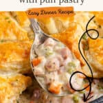 A spoon lifts creamy ham and vegetable pot pie filling from a puff pastry-topped dish.