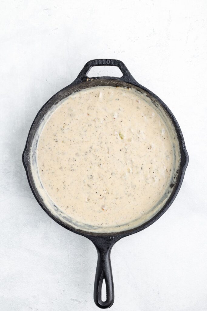 Creamy sauce with herbs in a black cast iron skillet.