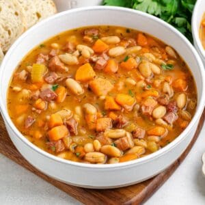 A bowl of ham and white bean soup with vegetables.