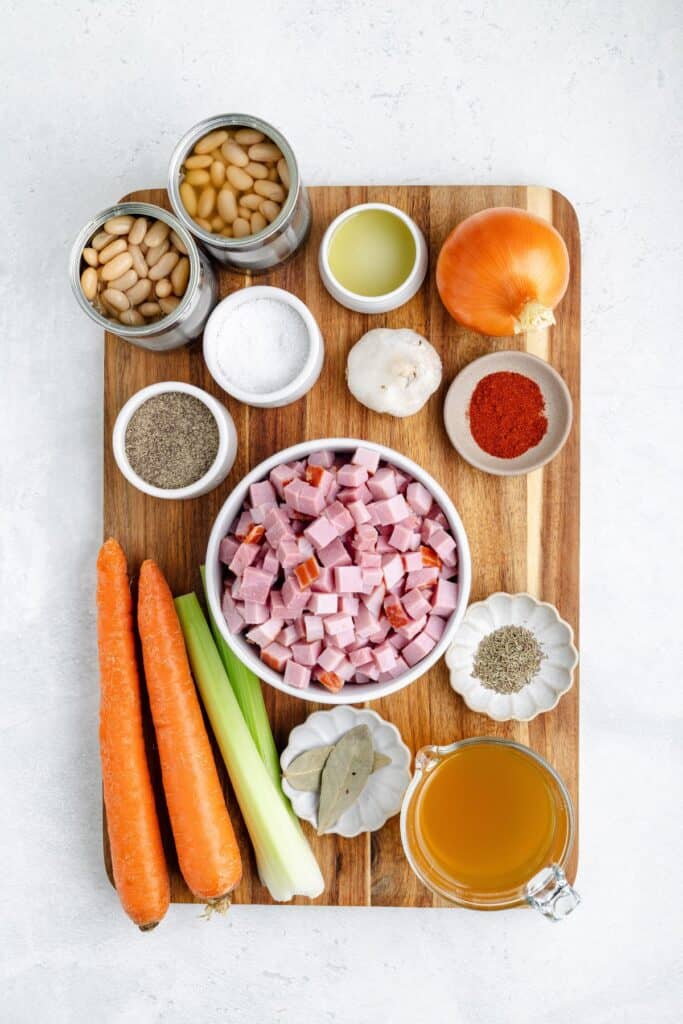 Diced ham, beans, and vegetables for soup arranged on a wooden cutting board.