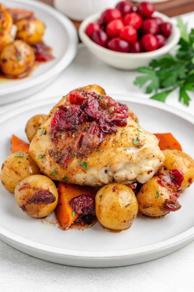 Roasted cranberry chicken and vegetables on a white plate.