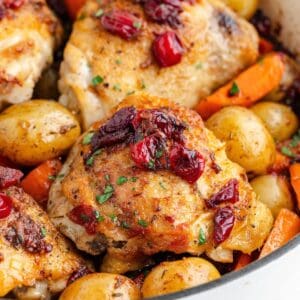 Roasted cranberry chicken thighs with vegetables in a pan.