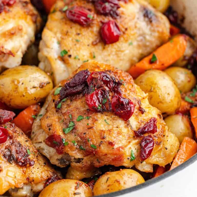 Roasted cranberry chicken thighs with vegetables in a pan.